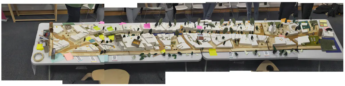 Looking to be the centrepiece of our exhibition, we proposed to create a site model of Dudley Highstreet at 1:200 scale with buildings modelled in a simple form. Local residents and visitors to the exhibition are then invited to decorate a chosen building to how they would envision it sat within the context of a greener Highstreet. We want to tie in our themes of biodiversity and materials by proposing that buildings can, and do, have the potential to be a lot healthier, sustainable, and interactive on the street. This site model also helps gain vital public opinions on the Highstreet and prompts discussion of areas most in need of attention.

To ensure that the model is utilising the MDF to the most efficient standard possible. First, the centres of the massing blocks have been hollowed out. This allows a reduction in materials used as other buildings can be cut in the centres of the model. Then the top is finished with a solid piece.
The waste material is placed into the recycling rack where other students can reuse it; otherwise, if the material left cannot be used for another project, it is recycled correctly by the university.

The model spanned just over 3.4m long and over 50cm wide. With the majority being cut from scrap woods that would fit the jigsaw of the shape, we were able to drastically cut down on waste. We also got some small benches and bee hives printed from recycled plastics, and used dried flowers as trees to represent the green spaces. Ultimately, the model seemed like a huge success, and really helped portray our ideas about Dudley High Street to those who came by. Everyone from Dudley who saw the model knew that it was the High Street, and interacted well with it. The size did make it difficult to move, especially to carry to the site, but it sat nicely in the centre of the the room and really drew people in to interact with it.

The model brought people in from outside to play with, write on, interact with. It became a spectacle for the public to come in and see what was happening and offer their ideas about what could be done.

The event was a success. Many people from the public (those who heard about the event, and those who just happened across it on the day) came in to interact with the model, which sat as the centre piece in the room. Kids liked to play with the pieces while the adults talked about things that could come from actions to help the High Street, not just leave it as is.

SOME OF THE KEY IDEAS WERE:
- The Shops need to be inviting for everyone. It’s no good having these places to go if people would rather take a bus to the next town.
- Just putting up boards across the windows is awful. Paint, Posters, Graffiti: Anything that actually makes the High Street look still alive is better than just wooden boards.
- More Green is needed. While it is obvious that there is a lack of Trees, many people wanted to push for these small bushes or planting spaces that could easily be implemented across the street.
- Spaces for public events or for people to at least gather at. While there is the Market and Fountain, it is not enough for the people of Dudley.
- Something needs to be done about the cars on the High Street. Some were Pro-Removal of all Cars, while some just wanted to limit when they could access the High Street.

Following the exhibition we created a series of drawings with our own interpretation of Sarah Wigglesworth ‘The Dining Table’ drawing. The drawings are a perfect representation of the our interactive model at the ERA Environmental Exhibition and Event. Showing the interaction the public had with the model, as well as the conversations that were held around the model. - Table 9.png